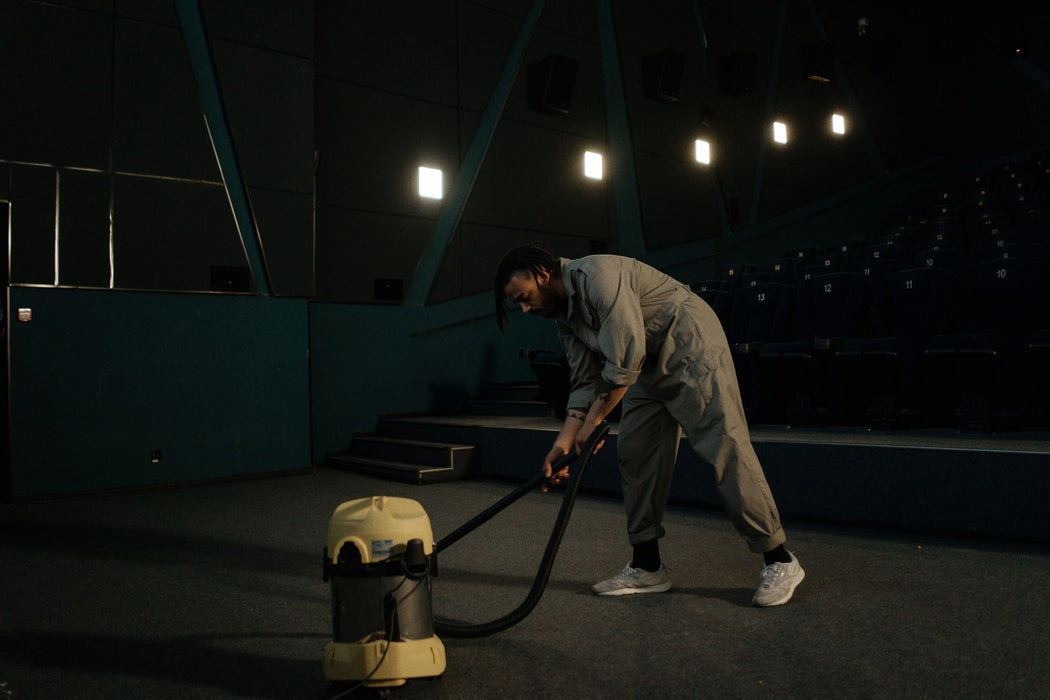 Worker vacuuming carpet in a commercial cinema setting