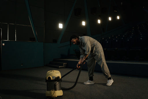 Worker vacuuming carpet in a commercial cinema setting